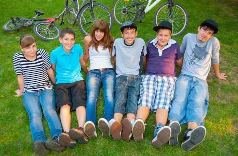 Un stage de néerlandais ou des cours particuliers ? Des élèves qui sourient en groupe allongés dans l'herbe.